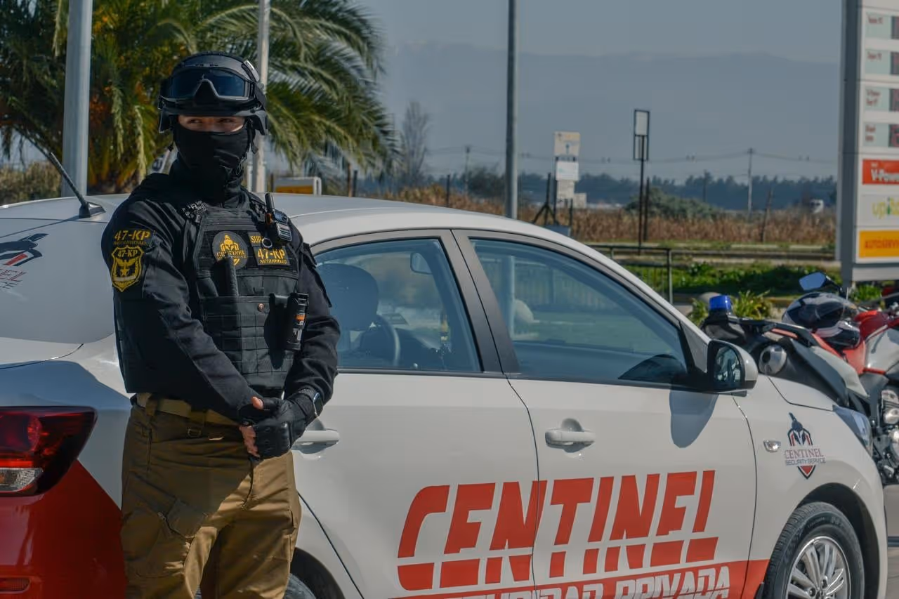 Guardia de control de acceso de Centinel junto a vehículo corporativo