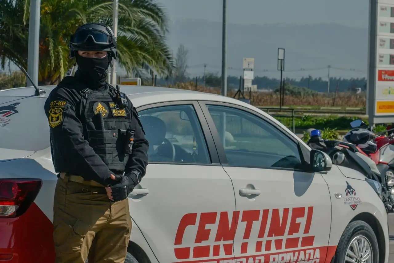 Guardia de control de acceso de Centinel junto a vehículo corporativo